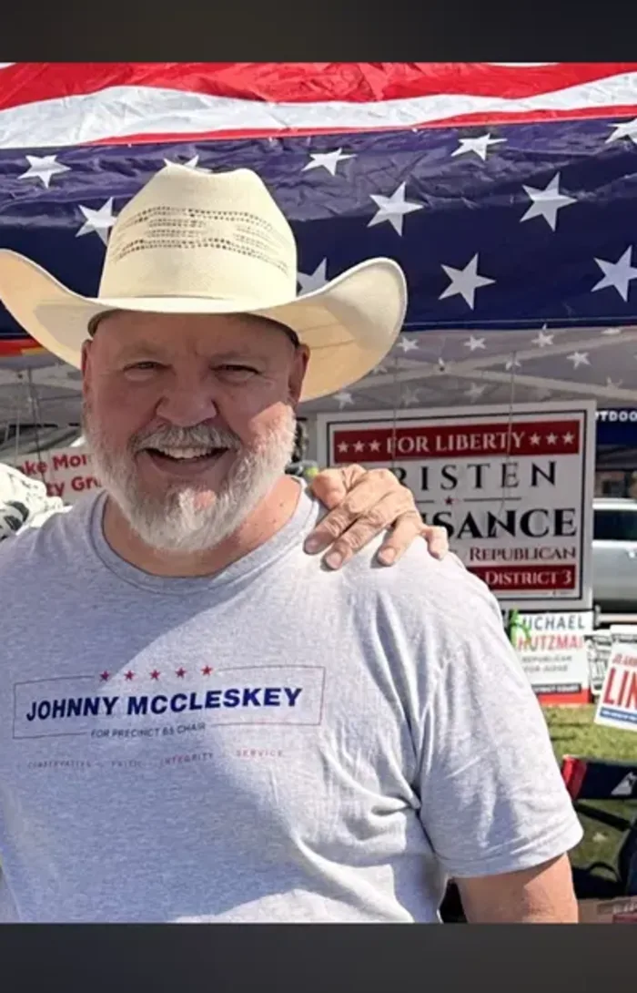 Johnny McCleskey in his Precinct 65 shirt, standing under an American flag at a community event in Magnolia, Texas